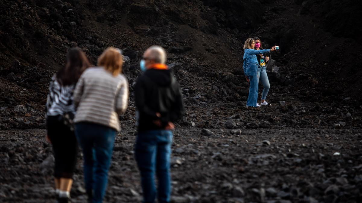 Archivo - Una pareja de turistas se hacen un &#039;selfie&#039; sobre la colada de lava del volcán de Cumbre Vieja