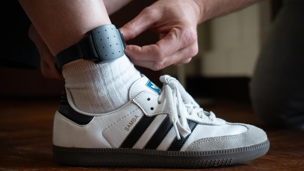 Una persona se coloca una pulsera telemática en el tobillo