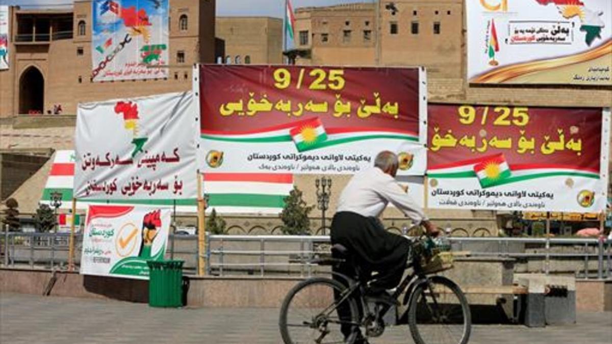 En campaña 8Un hombre en bicicleta pasa ante carteles por el referéndum de autodeterminación del Kurdistán, ayer, en Erbil.