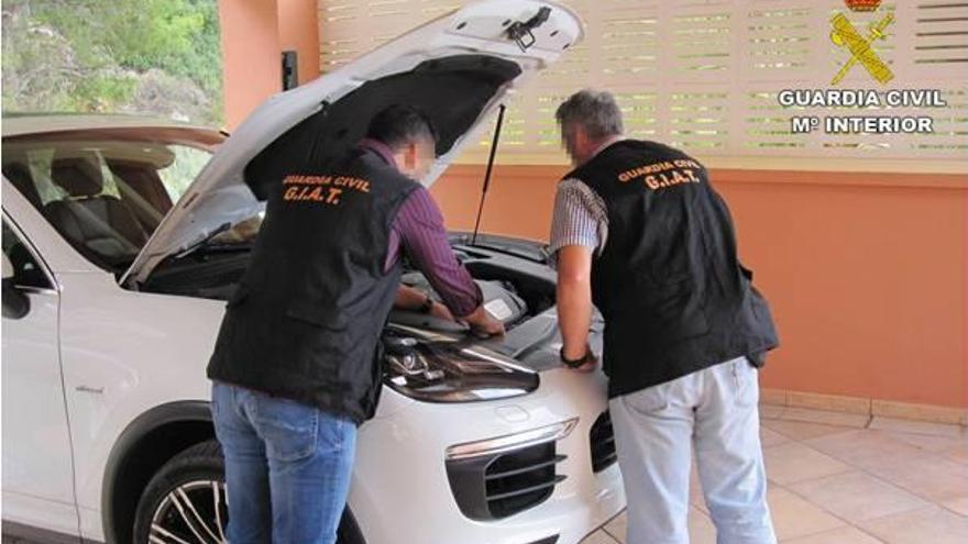 Dos agentes de la Guardia Civil examinan uno de los coches incautados.