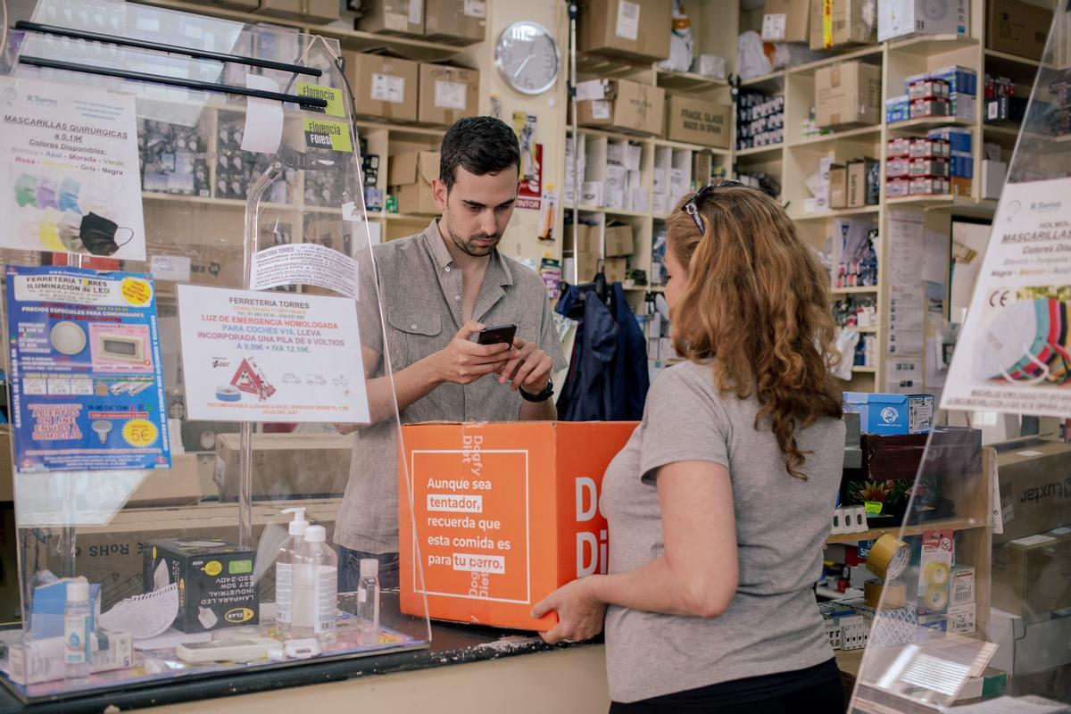 Alejandro, trabajador de la Ferretería Torres, pasa el lector de códigos por un paquete que le pasa Rosana