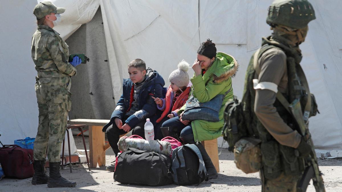 Una mujer sentada con niños evacuados del área cerca de la planta siderúrgica Azovstal en Mariupol, llegan a un centro de alojamiento temporal durante el conflicto Ucrania-Rusia en la aldea de Bezimenne en la región de Donetsk, Ucrania.