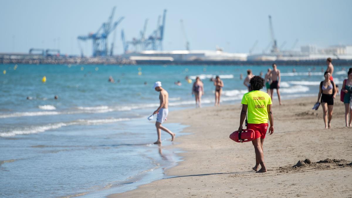 Un socorrista recorre la playa del Grau y contempla desde la orilla a los numerosos bañistas.