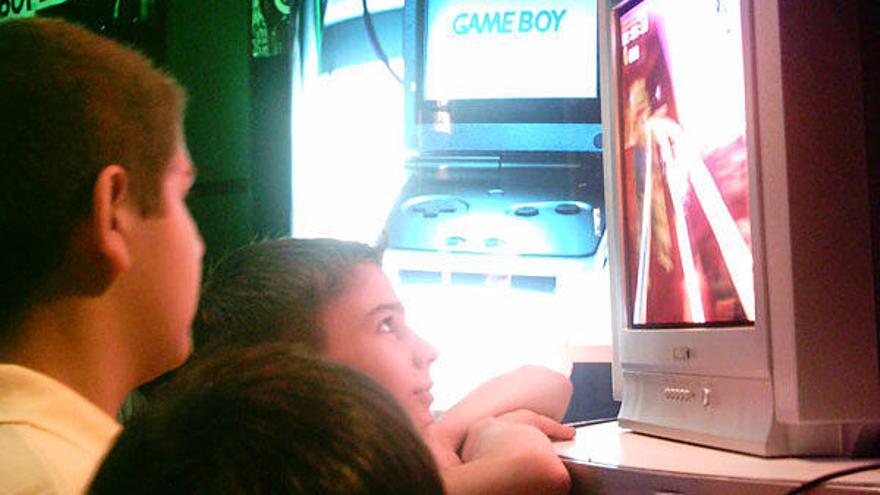 Unos niños observan el desarrollo un videojuego en un establecimiento comercial.