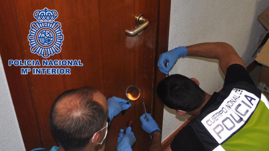 Dos agentes trabajan buscando pistas en la puerta de una casa asaltada.