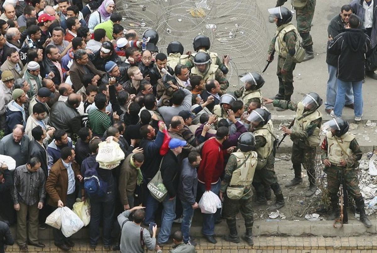Un grup de manifestants esperen darrere una barricada abans que soldats egipcis els registrin per accedir a la plaça de Tahrir al Caire avui, dissabte. Un grup de manifestants esperen darrere una barricada abans que soldats egipcis els registrin per accedir a la plaça de Tahrir al Caire avui, dissabte.