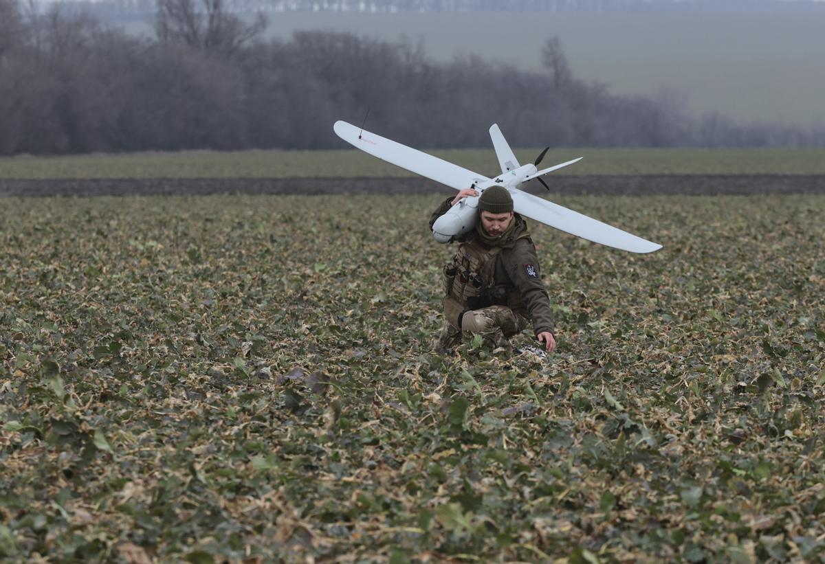 Un militar ucraniano de la Brigada de Defensa Territorial lleva un dron de fabricación ucraniana en un campo cerca de la línea del frente en dirección a Zaporizhzhia, Ucrania,. 