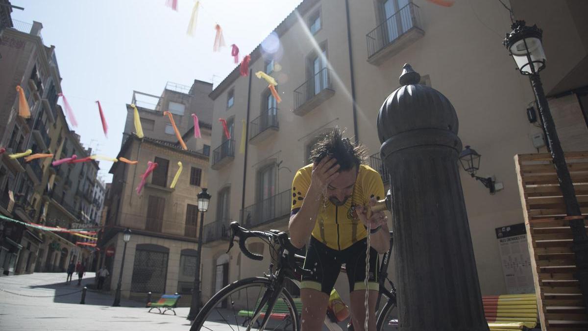 Un ciclista es refresca a la font de la Plana de l’Om de Manresa