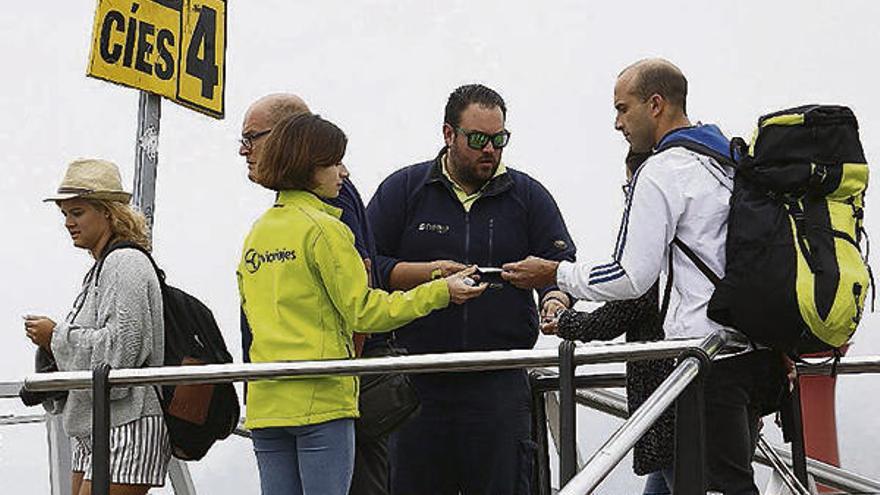Viajeros a Cíes muestran sus billetes ayer antes de acceder al barco. // Ricardo Grobas