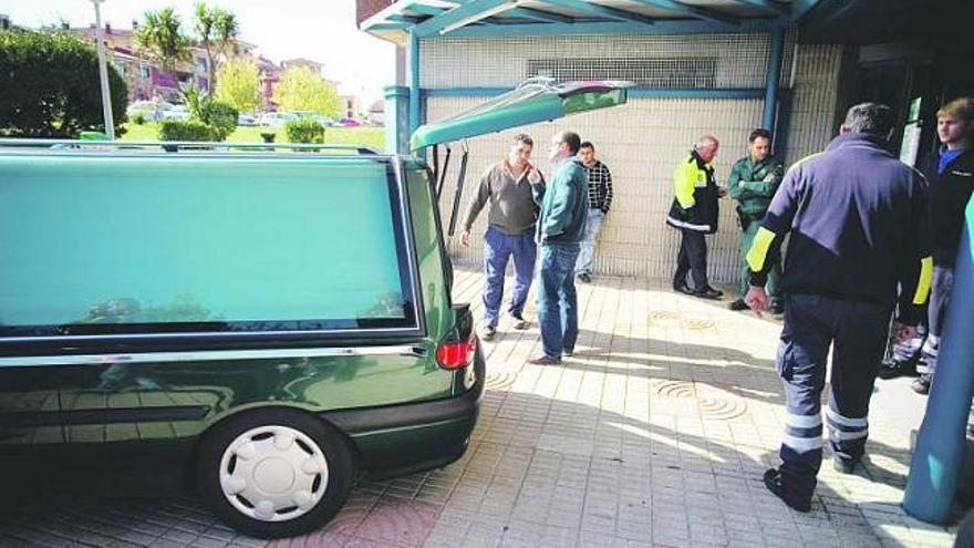 El coche fúnebre, efectivos de emergencias y familiares de la víctima, en el consultorio de Soto del Barco.