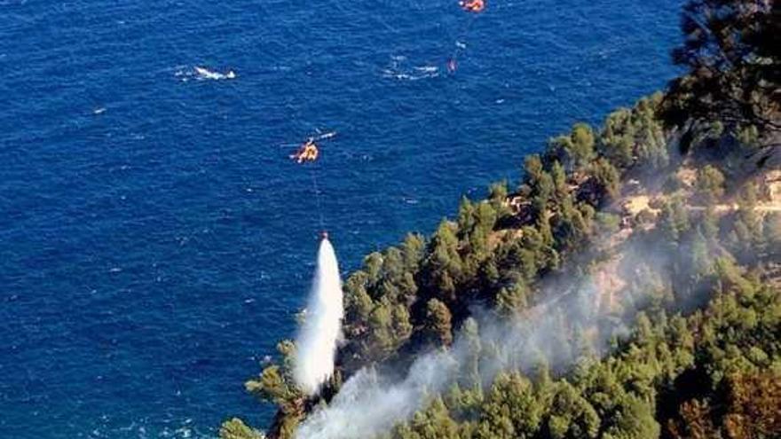 Medios aéreos atacan el fuego en una ladera.