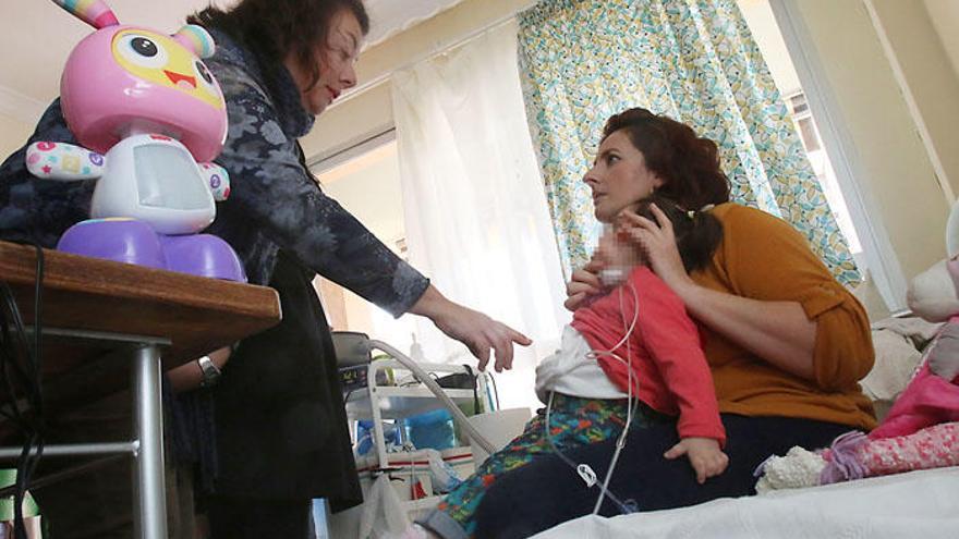 Profesionales de la Unidad de Cuidados Paliativos del Materno visitan a Alejandra María, a la que ajustan su oxígeno.