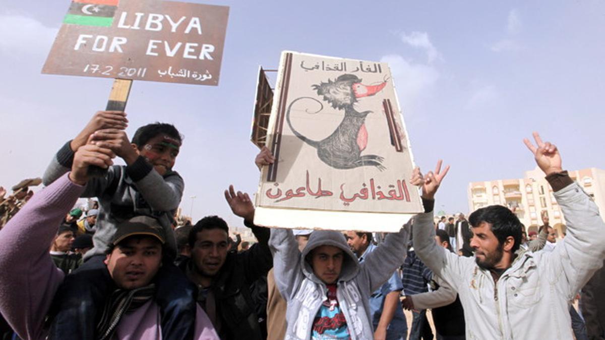 Manifestantes enarbolan pancartas contra Gadafi en Tobruk, en la costa de Libia.