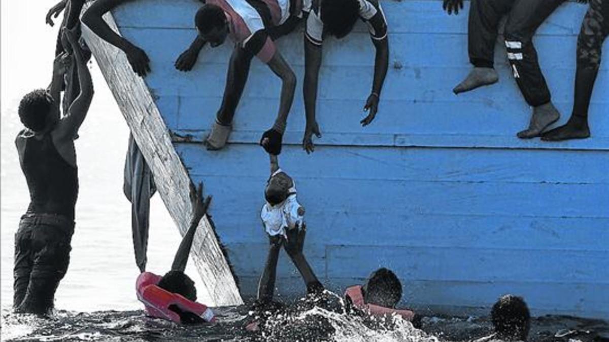 28/11/2016 Migrantes tratan de sacar a un niño del mar a 12 millas náuticas de Libia.