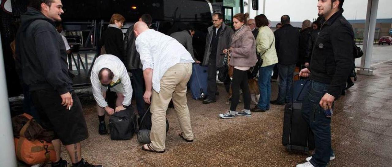 Varios pasajeros, bajándose de un autobús en el aeropuerto de Asturias.