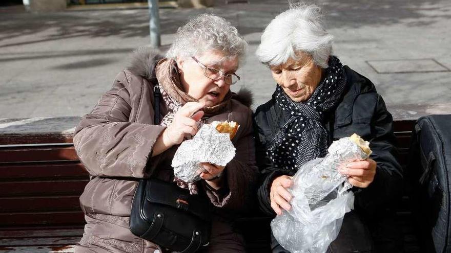 Dos mujeres conversan durante el almuerzo sentadas en un banco de la plaza Castilla y León.