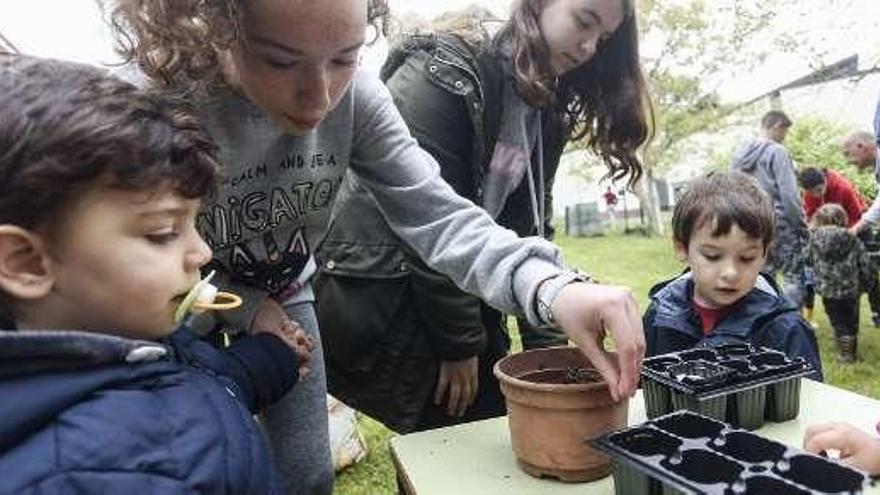 Dos alumnas de la ESO enseñan a un grupo de niños de El Texu a plantar.