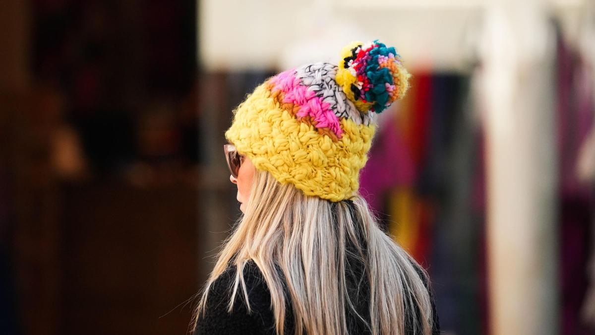 Una transéunte por la calle protegiéndose del frío con un gorro