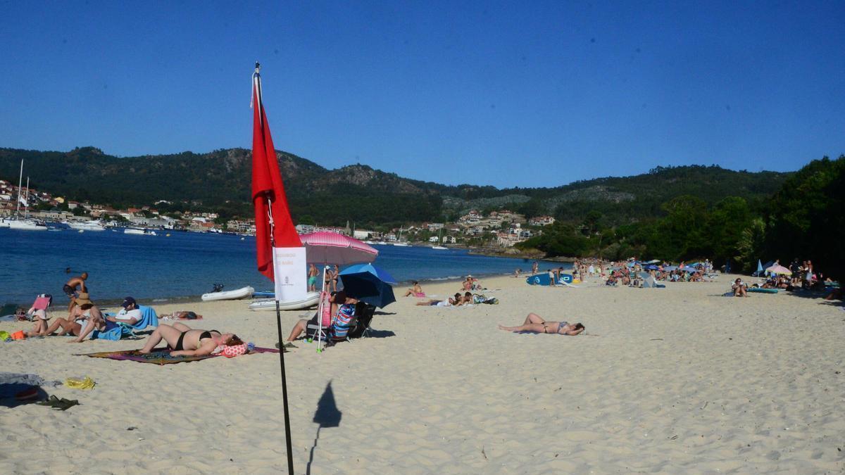 Playa de Arneles, con la bandera roja y los barcos fondeados en segundo plano.