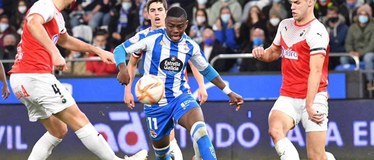 William de Camargo, entre dos rivales del Racing de Santander, durante el partido contra el equipo cántabro en Riazor. |  // VÍCTOR ECHAVE