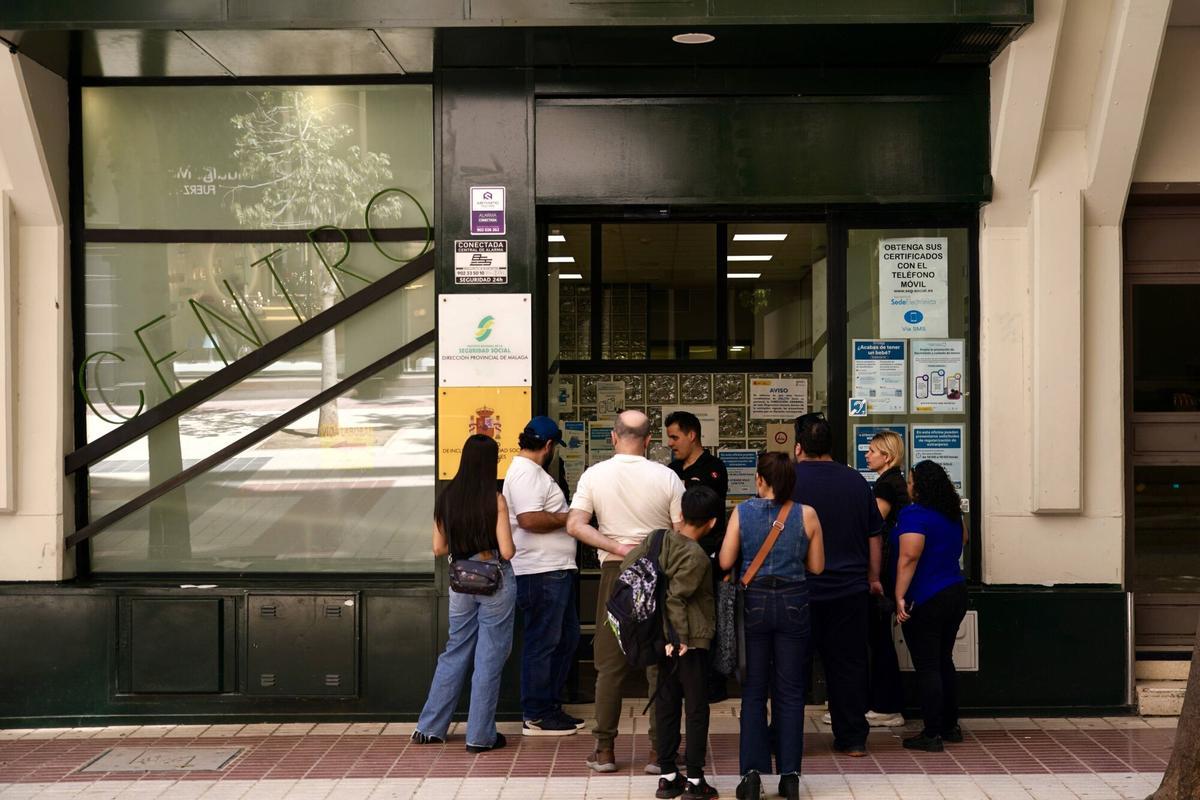 Varios migrantes esperan en la puerta de la oficina de la Seguridad Social de calle Huéscar