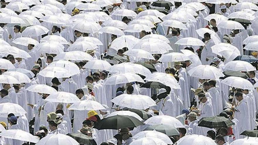 Un grupo de clérigos, cubiertos con paraguas, en la misa. // Efe