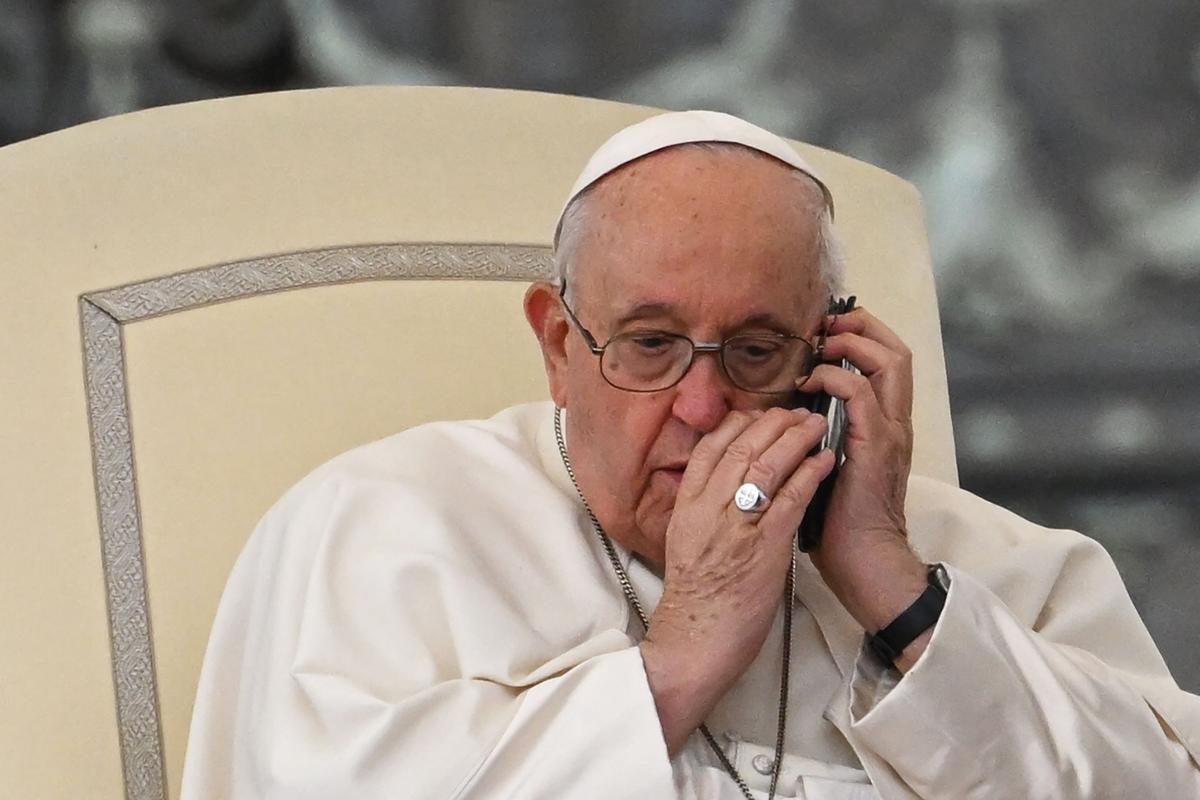 El Papa Francisco habla por teléfono durante la audiencia general semanal en la plaza de San Pedro.