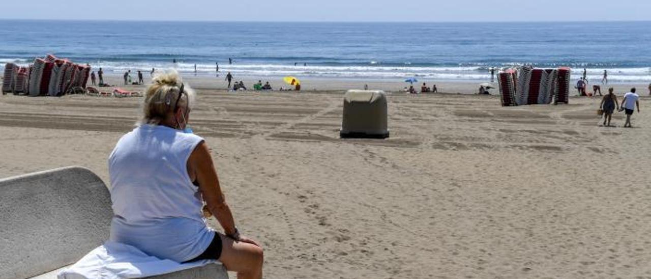 Una mujer descansa en un banco en Playa del Inglés. |