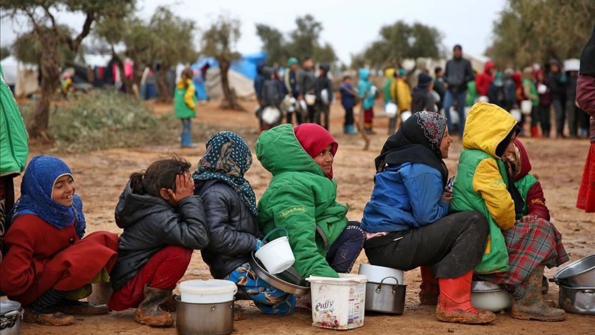 Niños esperan a recibir alimentos en el campo de refugiados sirio de Yazi Bagh.