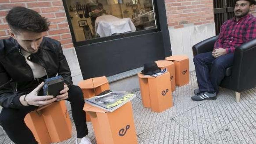 Víctor Álvarez (izquierda) y Ramón González, en el exterior de la barbería de Jorge Cueto, mientras éste afeita a Roberto Bayón en el interior.