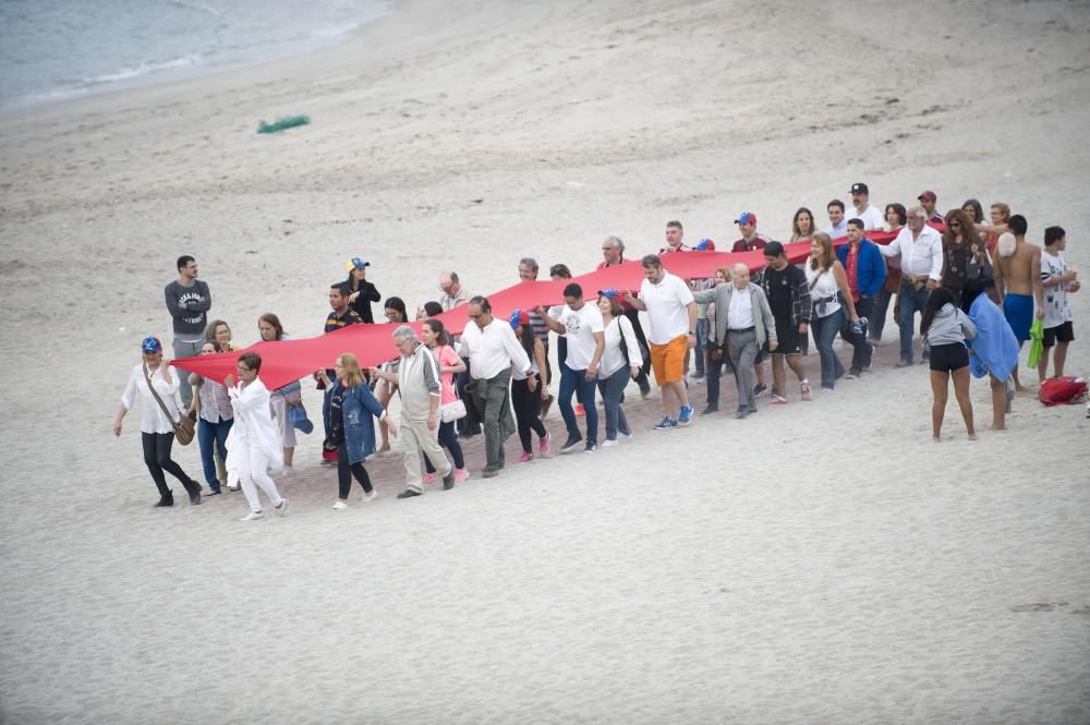 La comunidad venezolana despliega en la playa de Riazor una bandera para exigir que su país sea "libre".