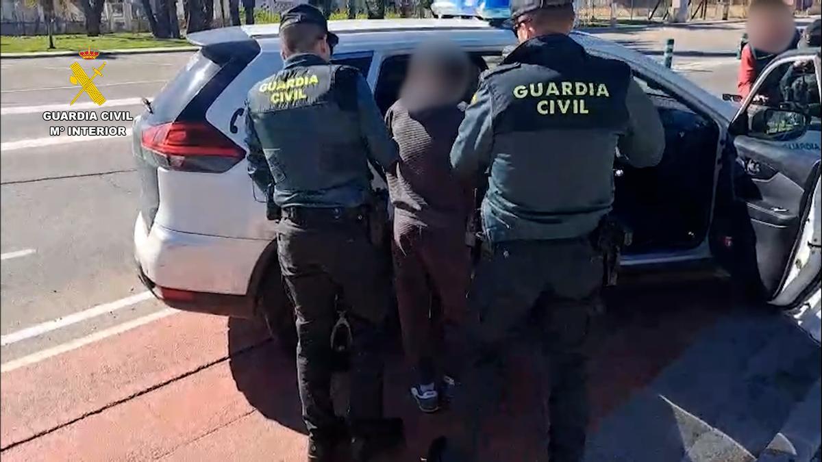 Uno de los detenidos al meterlo los agentes en el coche policial