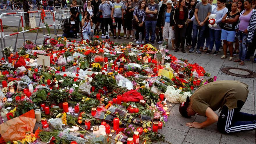 Un hombre reza en Múnich delante un altar de flores.