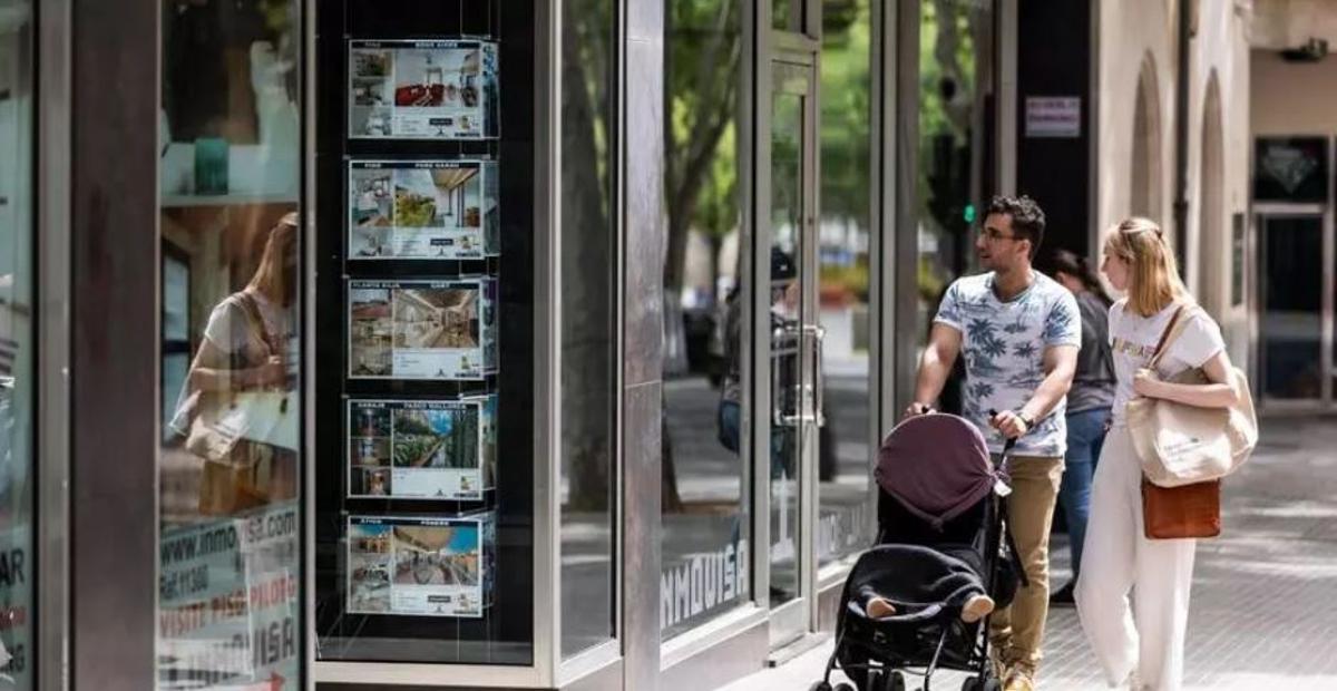 Dos personas observan los anuncios de viviendas en venta en una inmobiliaria en Palma. / EP