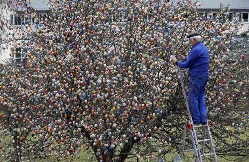 German pensioner Kraft decorates tree with Easter eggs in garden of his summerhouse in Saalfeld