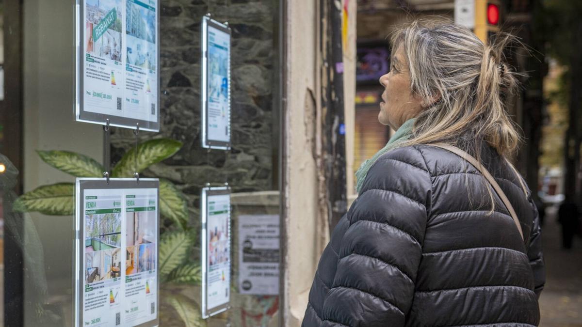 Una mujer revisa las ofertas de viviendas expuestas en el escaparate de una inmobiliaria en una imagen de archivo.