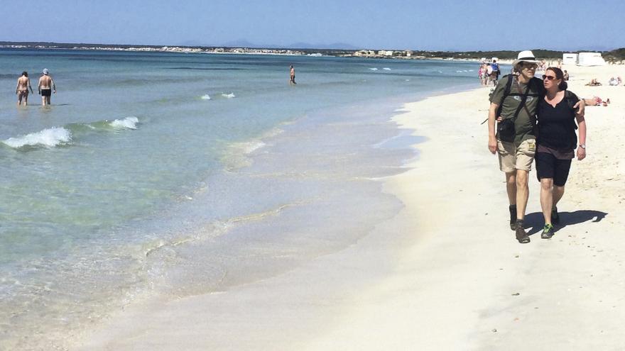 Una pareja camina por la orilla de la playa de es Trenc