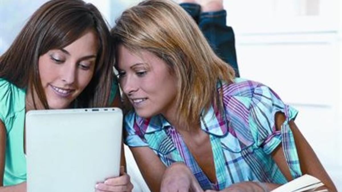 Dos jóvenes, con un libro y una tableta digital, dos formas de leer.