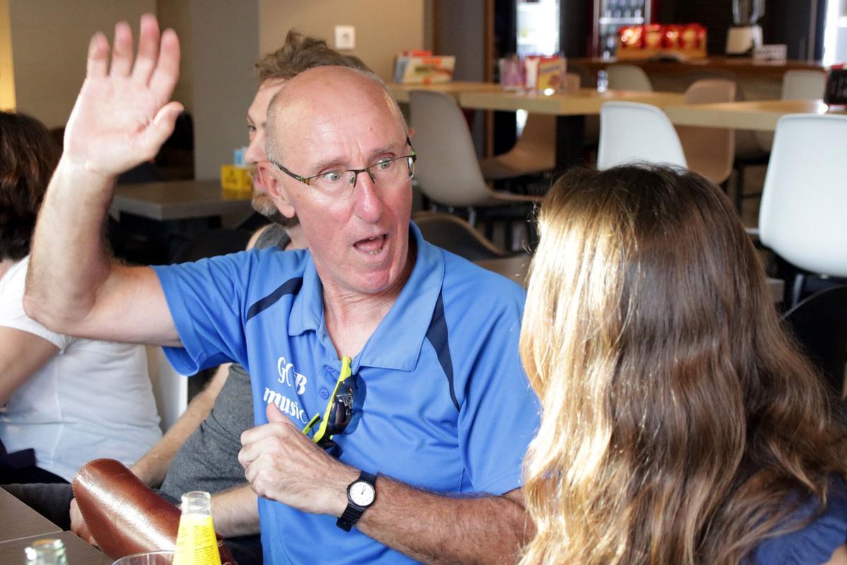 Primer pla d'un assistent a la trobada que fa el gest de saludar amb la mà