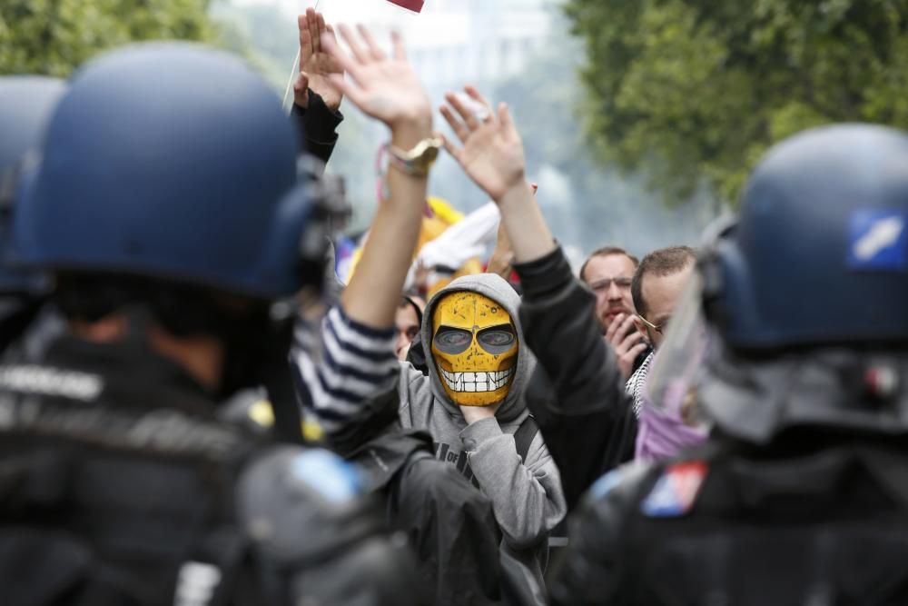 Jóvenes enmascarados frente a la policía durante una manifestación en París