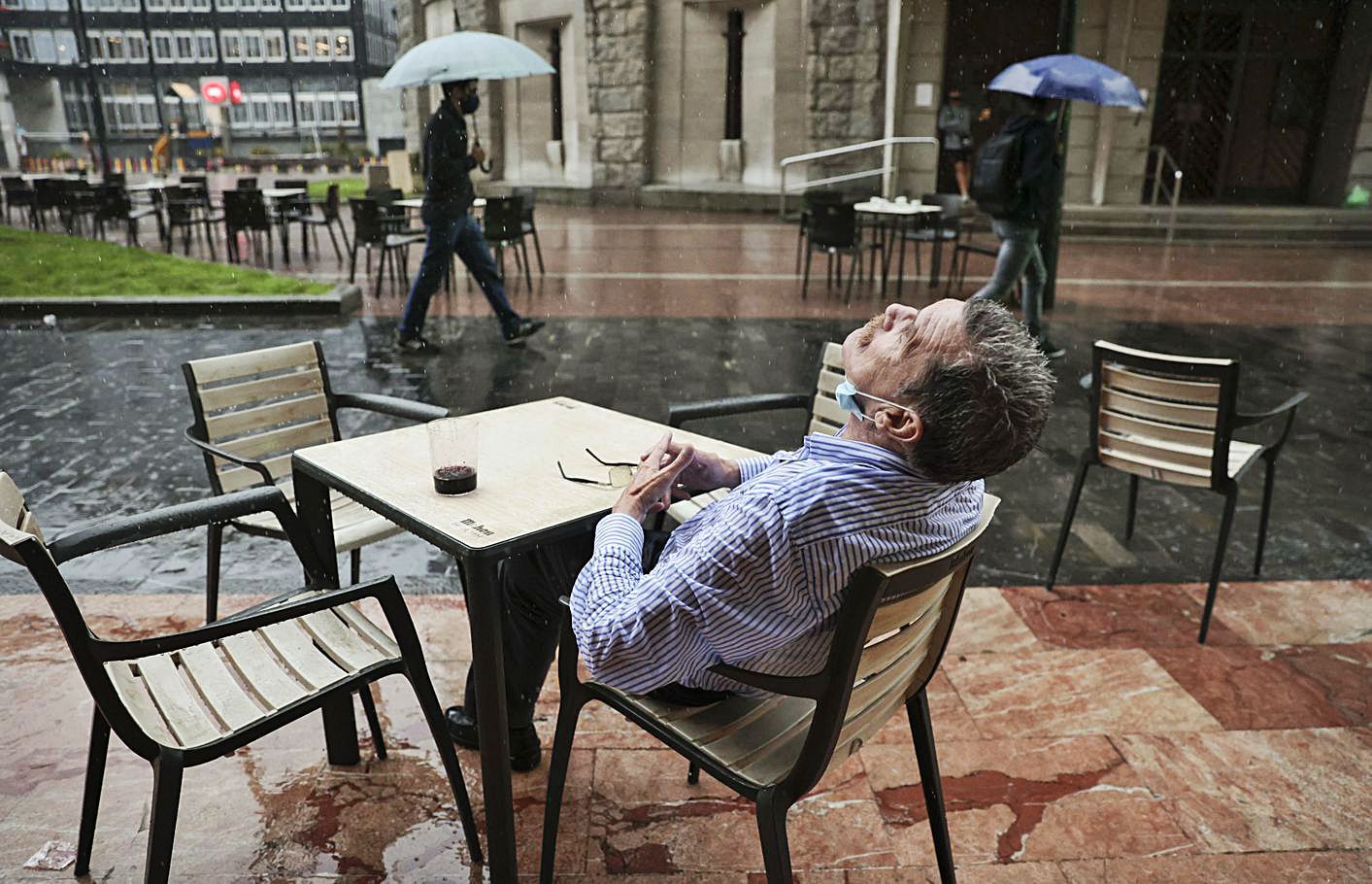 Un vecino de Oviedo disfruta de la lluvia en una terraza de la plaza de Fresno, en Oviedo. | Irma Collín
