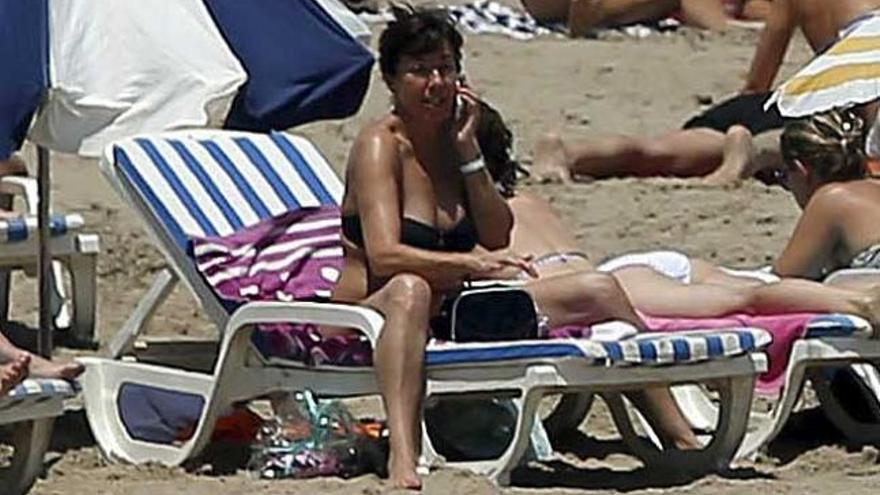 Una mujer habla por el móvil en la playa.