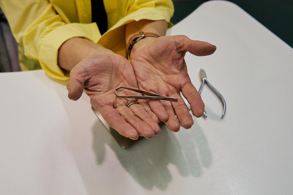 Caty mostrando una de sus reliquias: las pinzas con las que comenzó su carrera profesional.