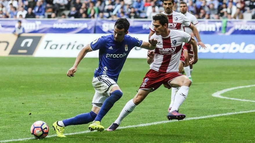 Linares controla ante dos defensas del Huesca.