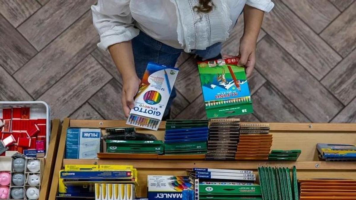 Una madre compra en un establecimiento material escolar.