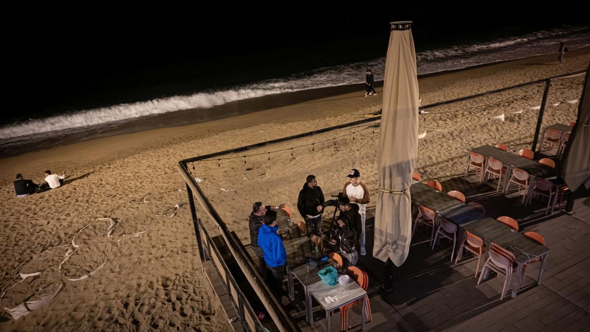 Barcelona 04/04/2021 Barcelona.
Botellon i ambiente en la Barceloneta sobre las 21:00h.
Grupo de jovenes bebiendo en unas mesas de una terraza de un restaurante cerrado por las restricciones. Barceloneta. 
AUTOR: Manu Mitru