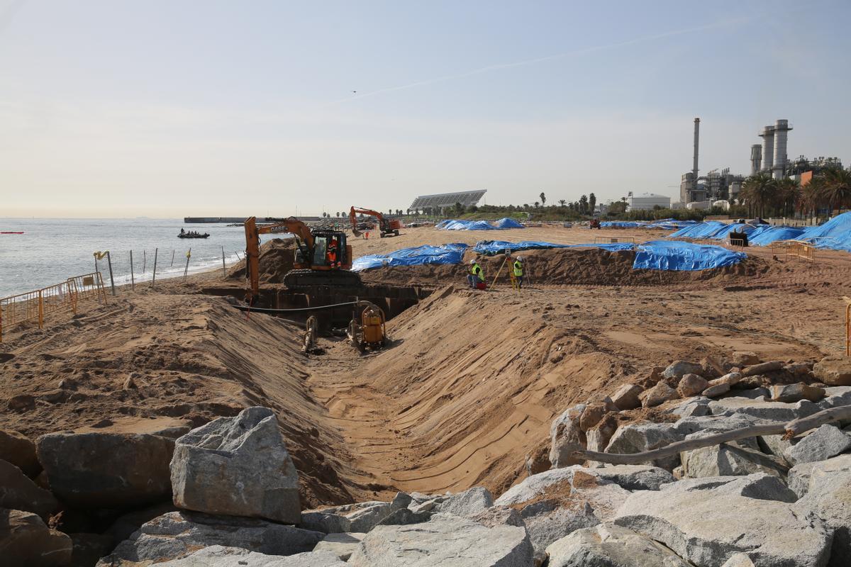 Operarios situados junto a la zanja abierta por las obras del cable submarino en la playa de Sant Adrià.