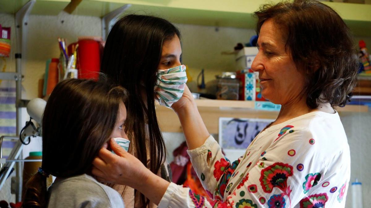 Una mujer prueba unas mascarillas a unas niñas, en Córdoba.