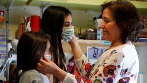 CO01. CÓRDOBA, 21/04/2020.- Una mujer prueba a dos niñas una mascarillas realizadas con un tamaño más pequeño para que puedan utilizarlas a partir del próximo lunes 27, tras el anuncio del Gobierno de que los menores de catorce años podrán acompañar a un adulto en las actividades que ya permite el estado de alarma, como ir al supermercado, a la farmacia o al banco. EFE/Salas