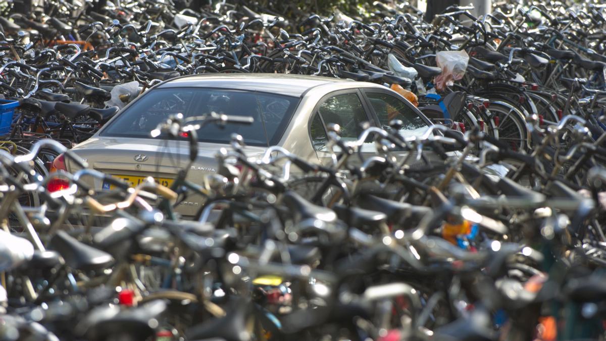 Un coche sepultado por las bicicletas aparcadas frente a la estación central de trenes en Amsterdam, Holanda